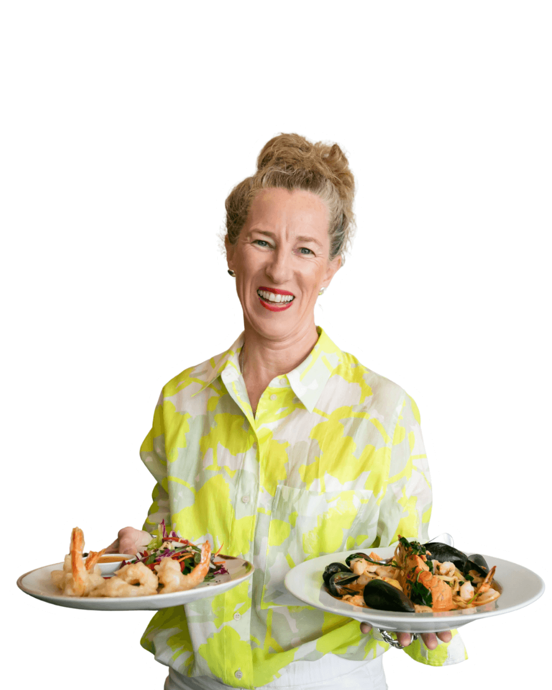 Woman holding two plates of food against a black background