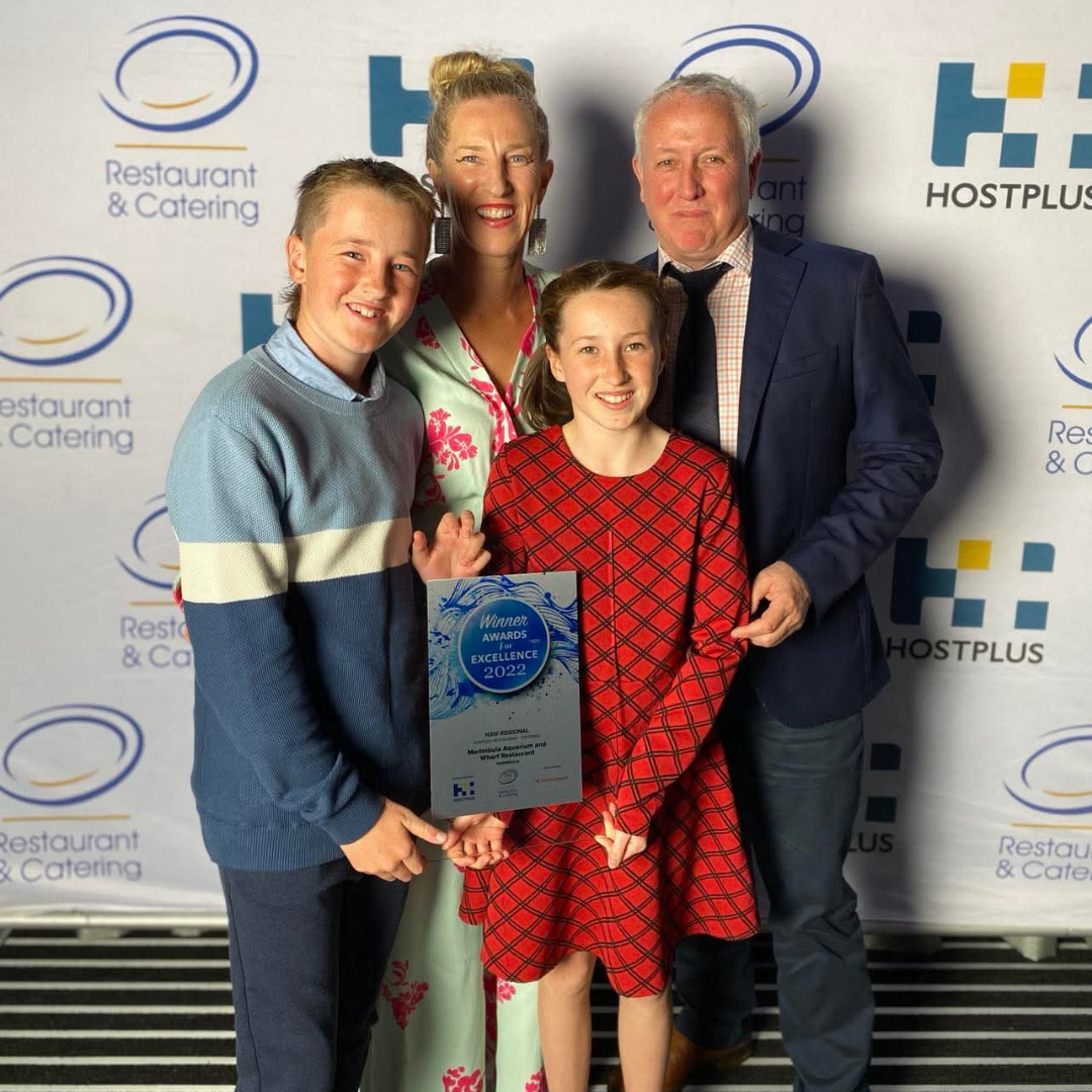 Family holding an award in front of a Hostplus and Restaurant & Catering backdrop