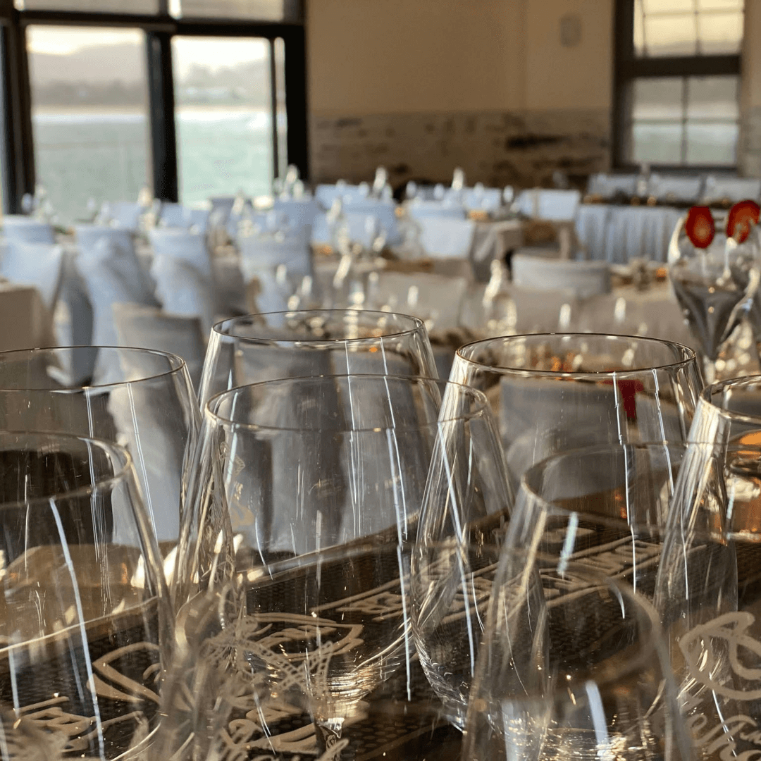 Clear white glasses on a table with a blurred indoor wedding event background